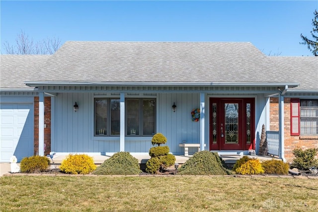 doorway to property with a porch, an attached garage, a shingled roof, and a yard