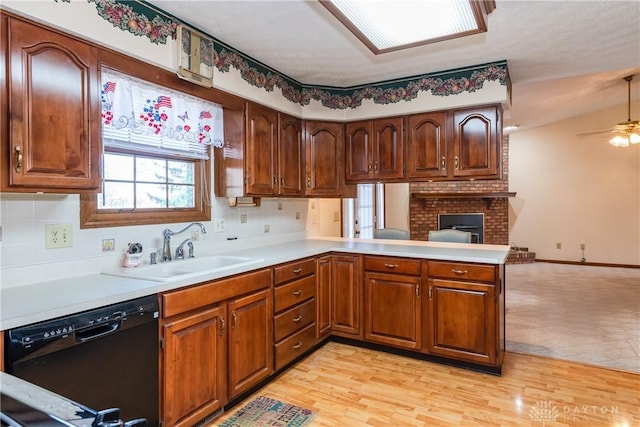 kitchen with a peninsula, light wood-style flooring, a sink, light countertops, and dishwasher