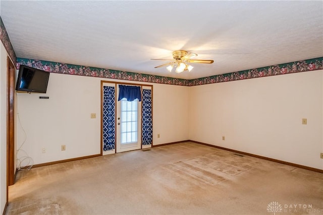 empty room featuring light carpet, visible vents, ceiling fan, and baseboards