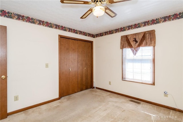 unfurnished bedroom with a closet, visible vents, light colored carpet, and baseboards