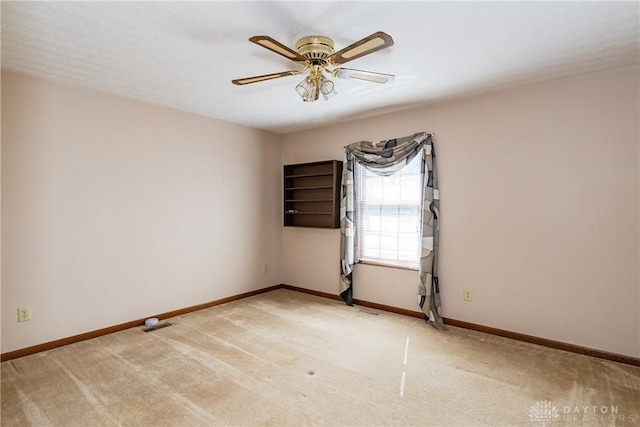 spare room featuring baseboards, light colored carpet, and ceiling fan