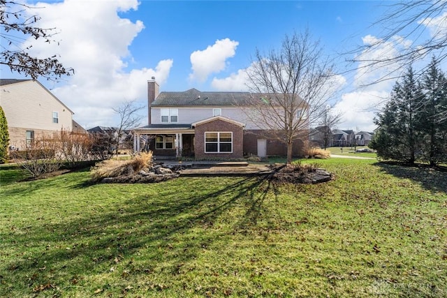 rear view of property with brick siding, a lawn, an attached garage, and a chimney