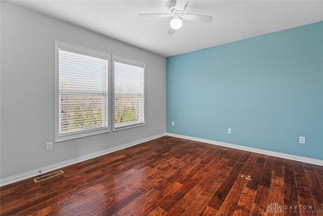 unfurnished room featuring dark wood-style floors, visible vents, a ceiling fan, and baseboards