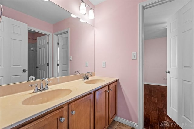 bathroom featuring double vanity, baseboards, and a sink