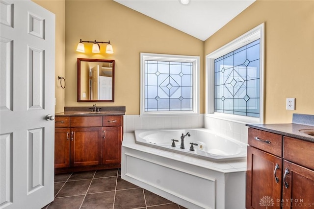 bathroom featuring vanity, a whirlpool tub, vaulted ceiling, and tile patterned flooring