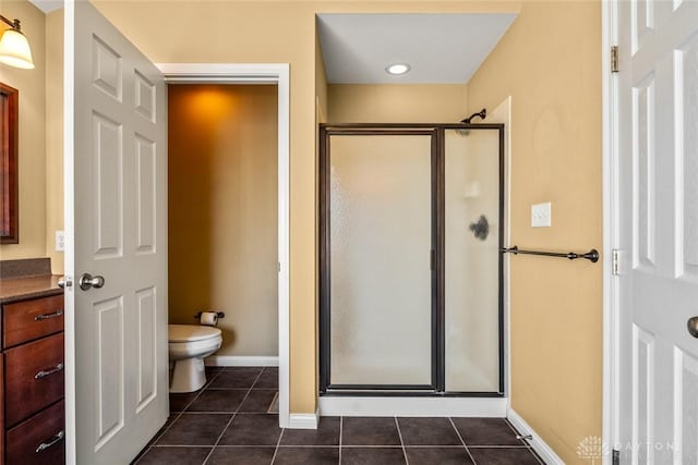 bathroom with tile patterned flooring, baseboards, toilet, a stall shower, and vanity