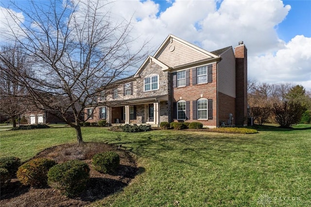 view of front of property featuring a front lawn, brick siding, stone siding, and a chimney