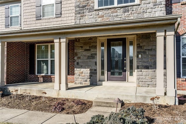 entrance to property featuring stone siding, brick siding, and covered porch