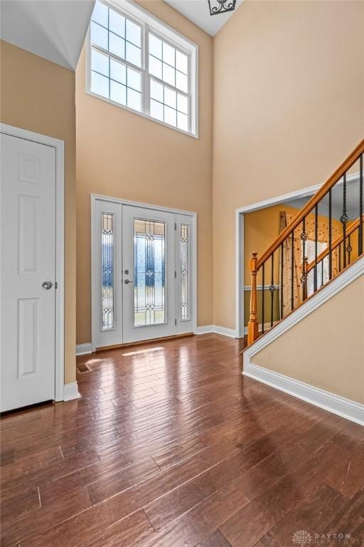 foyer with stairs, wood finished floors, baseboards, and a towering ceiling