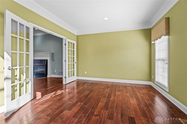 empty room with wood finished floors, french doors, a fireplace with flush hearth, and ornamental molding