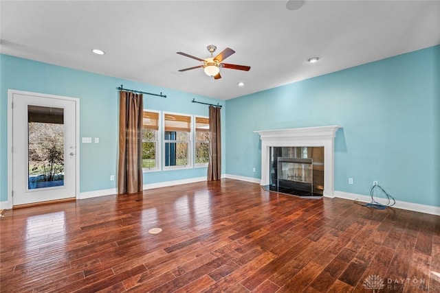 unfurnished living room featuring a ceiling fan, wood finished floors, baseboards, recessed lighting, and a tile fireplace