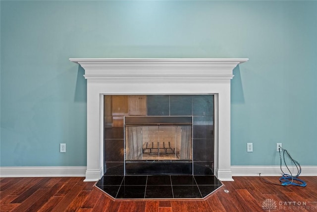 details with a tile fireplace, baseboards, and wood finished floors