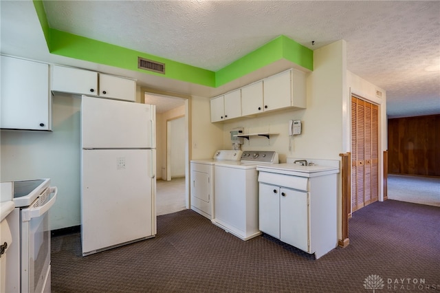 kitchen featuring white appliances, visible vents, a textured ceiling, dark colored carpet, and washer and clothes dryer