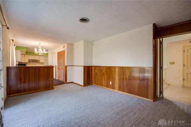 interior space with a wainscoted wall, a textured ceiling, and carpet