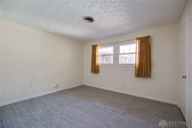 spare room featuring baseboards, visible vents, carpet floors, and a textured ceiling