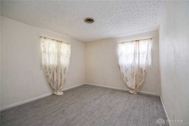 empty room with visible vents, baseboards, carpet floors, and a textured ceiling