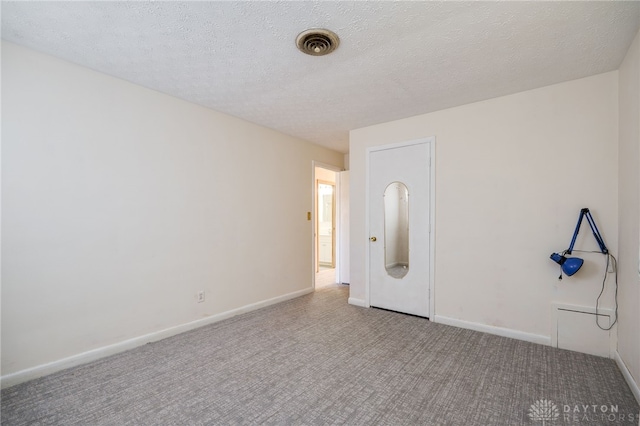 spare room featuring baseboards, visible vents, carpet floors, and a textured ceiling