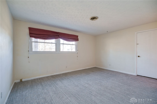 carpeted spare room featuring visible vents, a textured ceiling, and baseboards