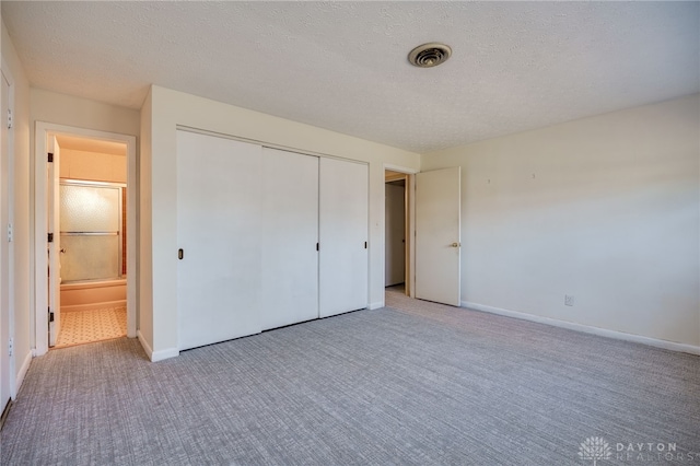 unfurnished bedroom featuring carpet, visible vents, a closet, and a textured ceiling