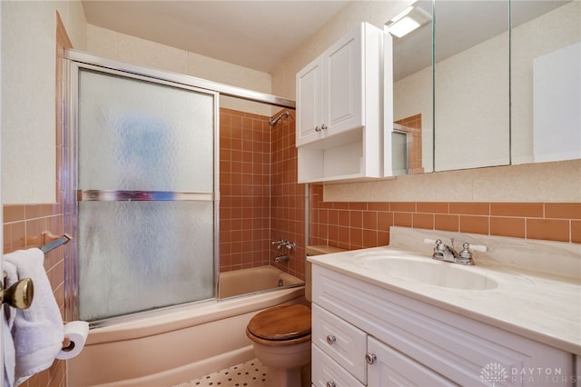 full bath with tasteful backsplash, toilet, vanity, enclosed tub / shower combo, and tile walls