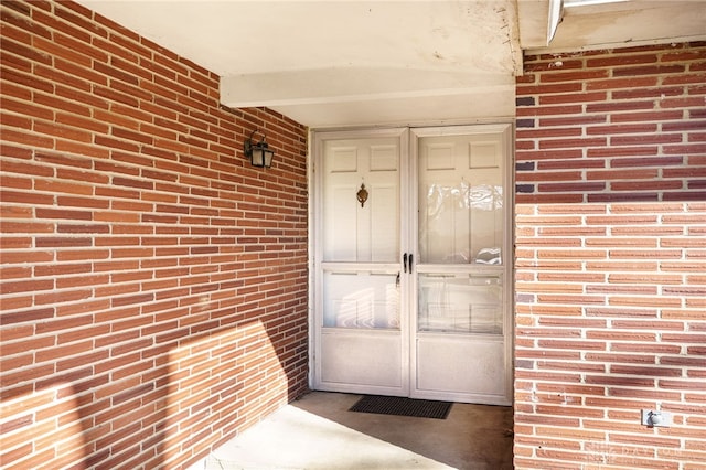 view of exterior entry featuring brick siding