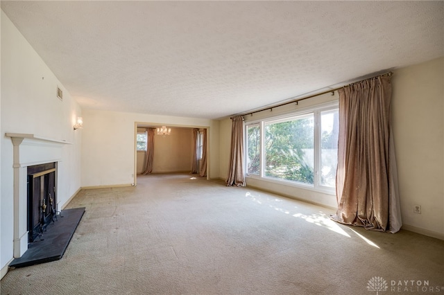 unfurnished living room with a notable chandelier, a textured ceiling, carpet, and a tile fireplace