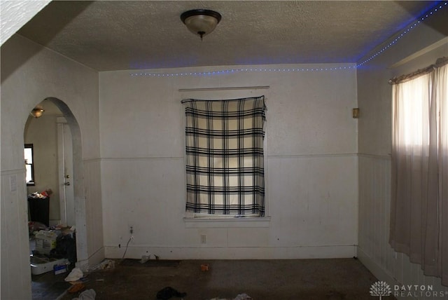 spare room with arched walkways and a textured ceiling