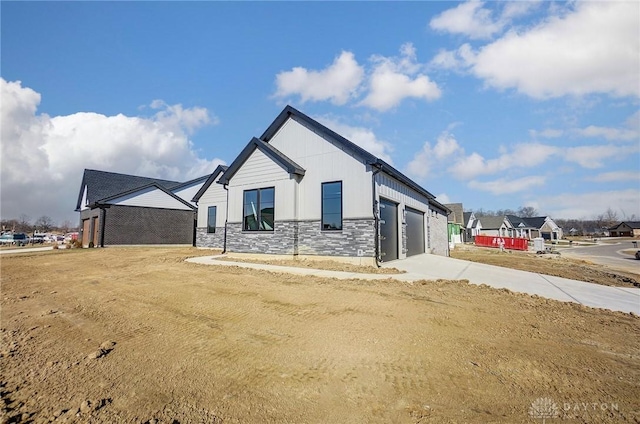 view of property exterior featuring stone siding, board and batten siding, concrete driveway, and an attached garage