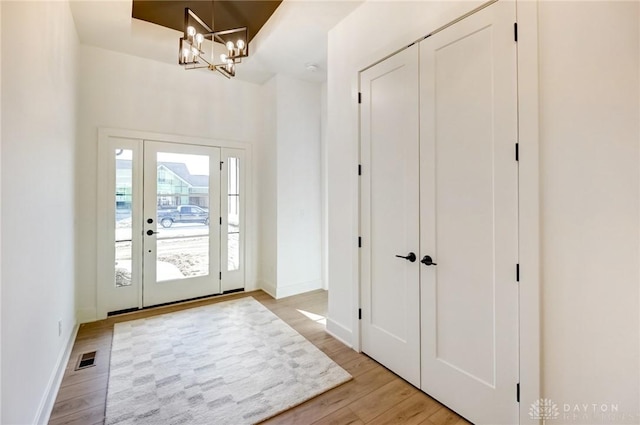 entryway featuring a notable chandelier, light wood-style floors, visible vents, and baseboards