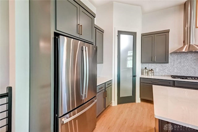 kitchen featuring decorative backsplash, light countertops, light wood finished floors, and appliances with stainless steel finishes