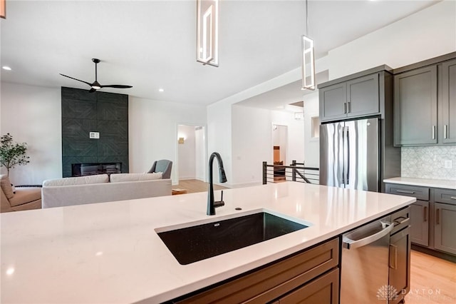 kitchen with tasteful backsplash, open floor plan, light countertops, appliances with stainless steel finishes, and a sink