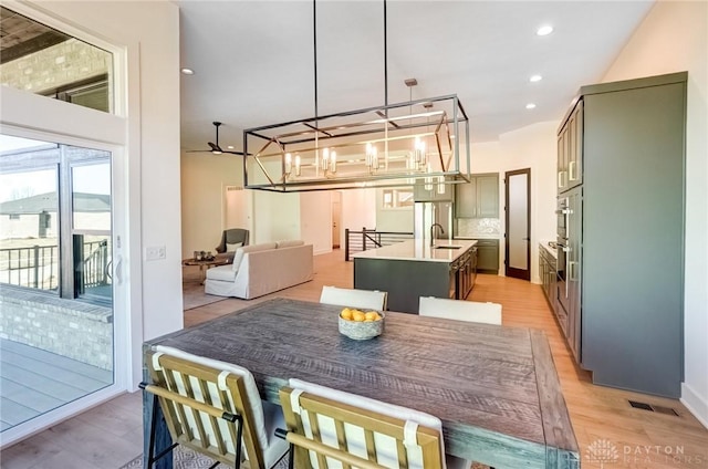 dining space featuring recessed lighting, light wood-type flooring, and a notable chandelier