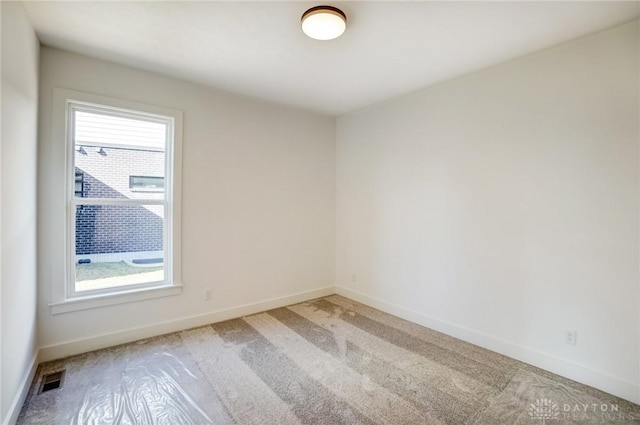 spare room featuring baseboards, a healthy amount of sunlight, and light carpet