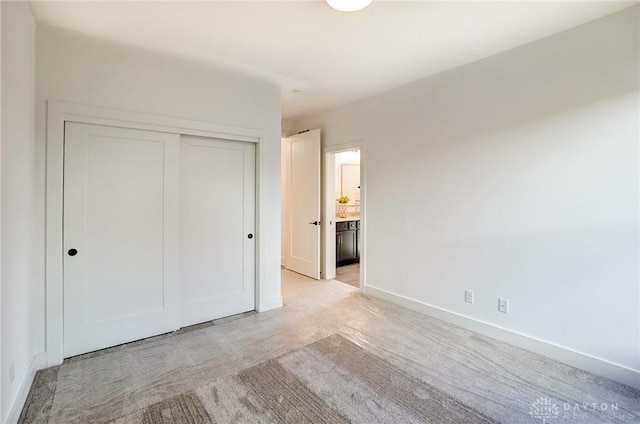 unfurnished bedroom with a closet, baseboards, and ensuite bathroom