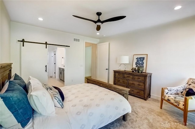 bedroom with a barn door, recessed lighting, visible vents, and light carpet