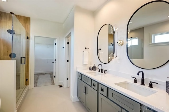 bathroom featuring a sink, a walk in closet, a stall shower, and double vanity