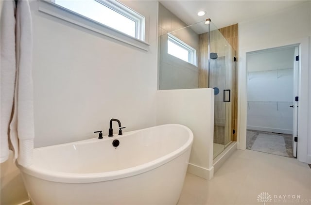 bathroom featuring a shower stall, a freestanding bath, and a walk in closet