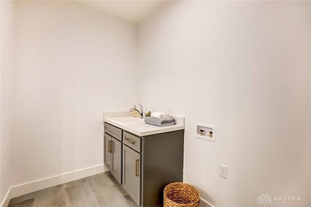 laundry room featuring cabinet space, washer hookup, baseboards, and a sink