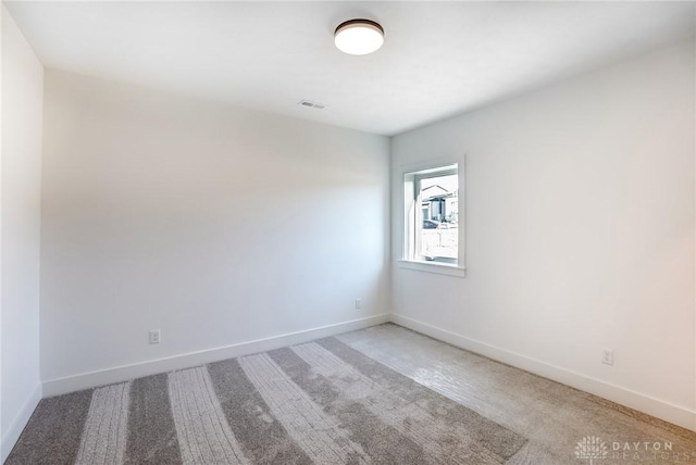 empty room with visible vents, baseboards, and light carpet