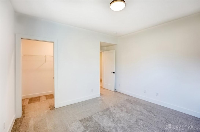 unfurnished bedroom featuring carpet, a walk in closet, and baseboards