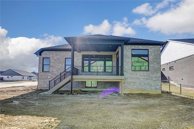 rear view of property with brick siding, stairs, and fence