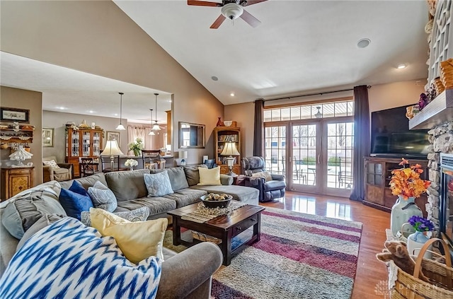 living area with a fireplace with raised hearth, recessed lighting, wood finished floors, high vaulted ceiling, and a ceiling fan