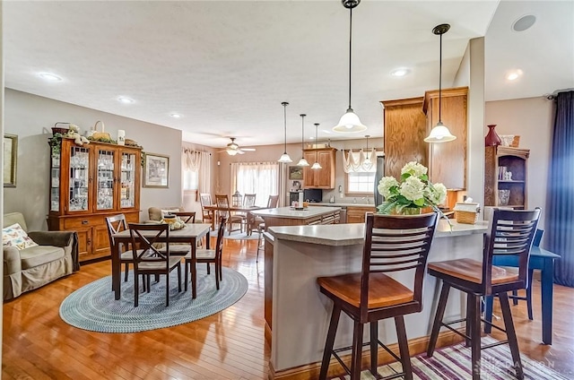 kitchen with a peninsula, a kitchen breakfast bar, light countertops, and light wood finished floors