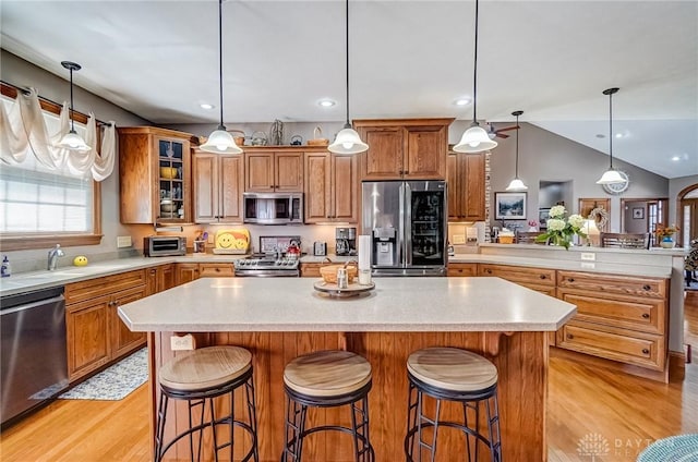 kitchen featuring glass insert cabinets, appliances with stainless steel finishes, light countertops, and light wood-style floors