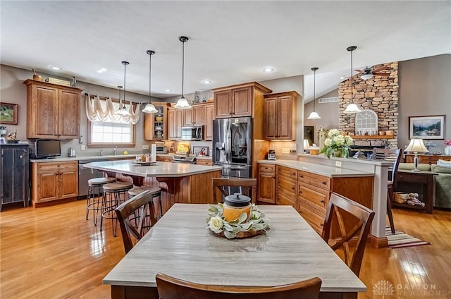 kitchen featuring a kitchen breakfast bar, appliances with stainless steel finishes, a center island, and brown cabinetry