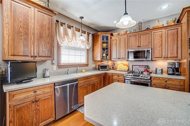 kitchen with pendant lighting, brown cabinets, appliances with stainless steel finishes, and a sink