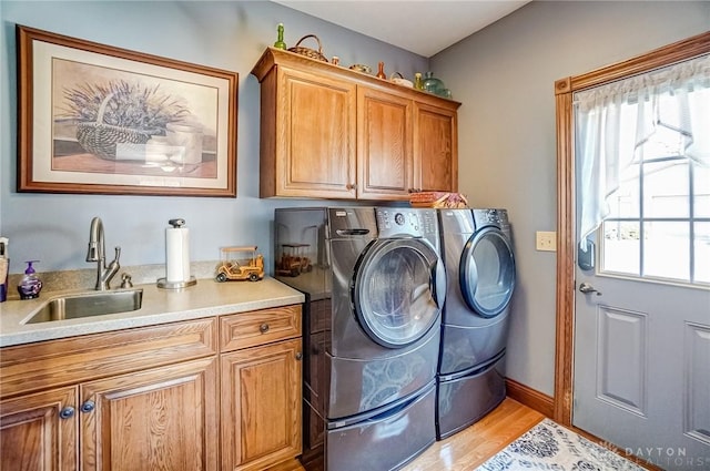 clothes washing area featuring separate washer and dryer, cabinet space, a healthy amount of sunlight, and a sink