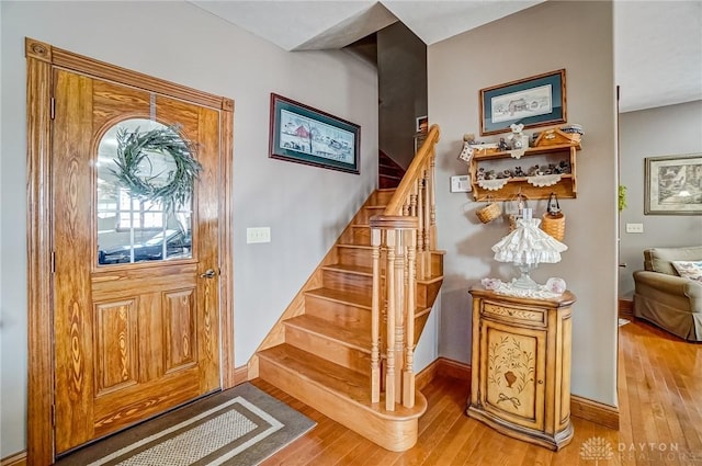 foyer featuring light wood finished floors, stairway, and baseboards