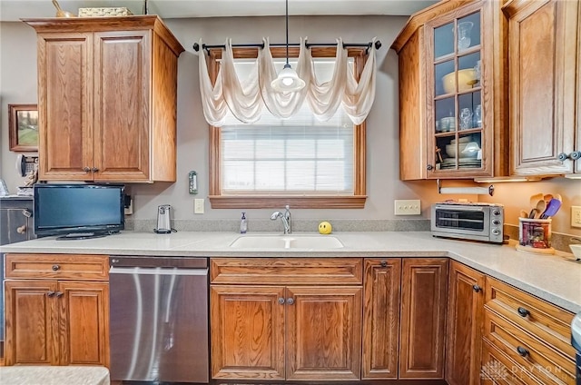 kitchen featuring glass insert cabinets, a toaster, dishwasher, light countertops, and a sink