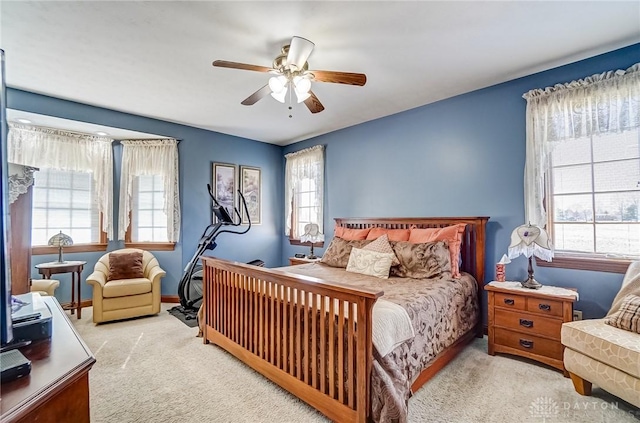 carpeted bedroom with multiple windows, baseboards, and a ceiling fan